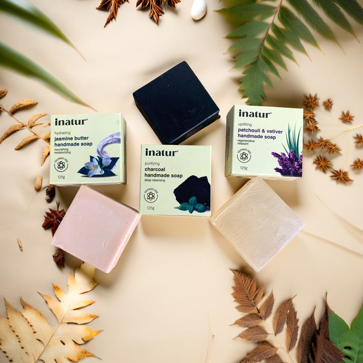 Collection of inatur handmade soaps with packaging on a decorative background with leaves and spices.